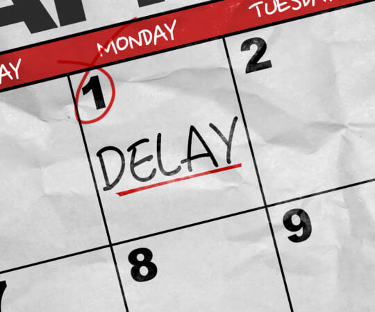 Close up of a calendar with the date "1" circled and the single word "Delay" written in black and underlined in red on the calendar.
