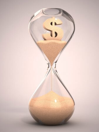 Hourglass with draining sand. A dollar sign is encased in the top half of the hour glass.